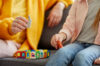 Woman in yellow sweater and child playing with toys in in-person therapy for kids